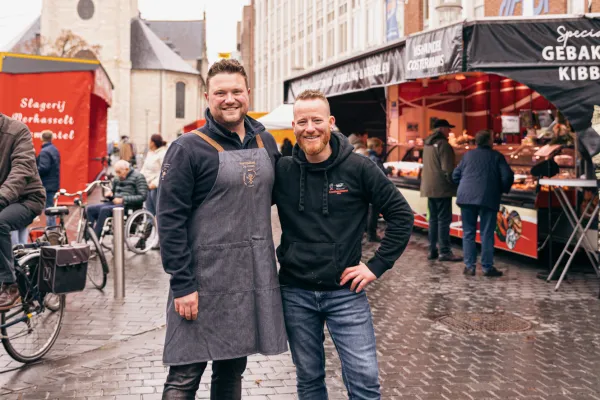 Twee jonge marktkramers poseren op de markt op het Kerkplein in Puurs