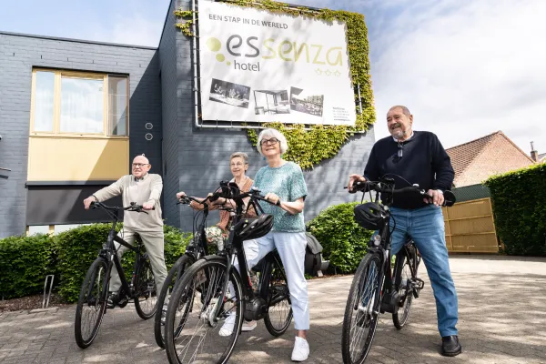Vier mensen met een fiets aan hotel Essenza