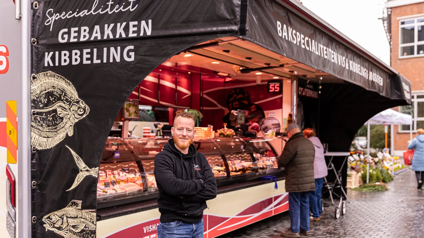 Marktkramer Nils Costermans poseert voor zijn kraam op het Kerkplein in Puurs